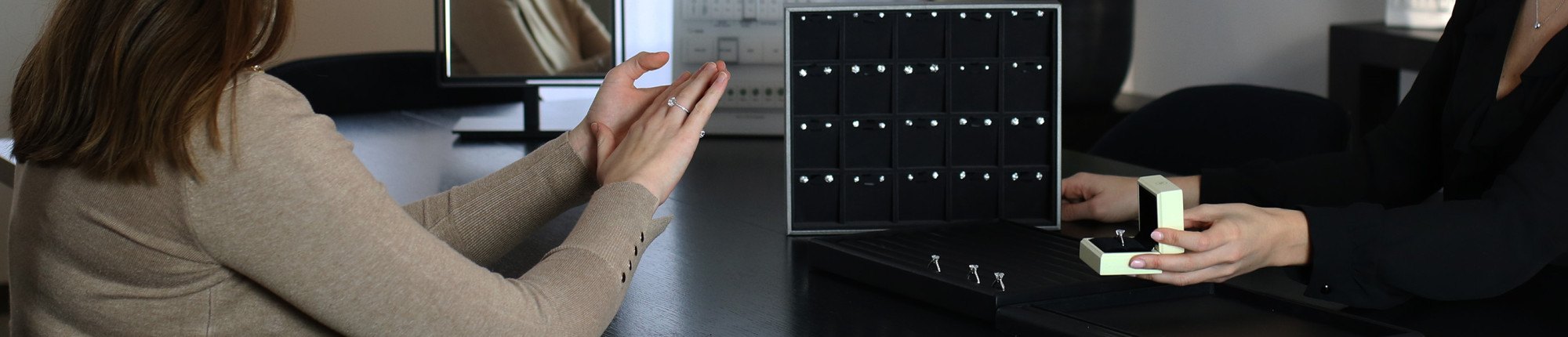 Jewelry consultation with diamond rings displayed in black presentation trays and a ring box