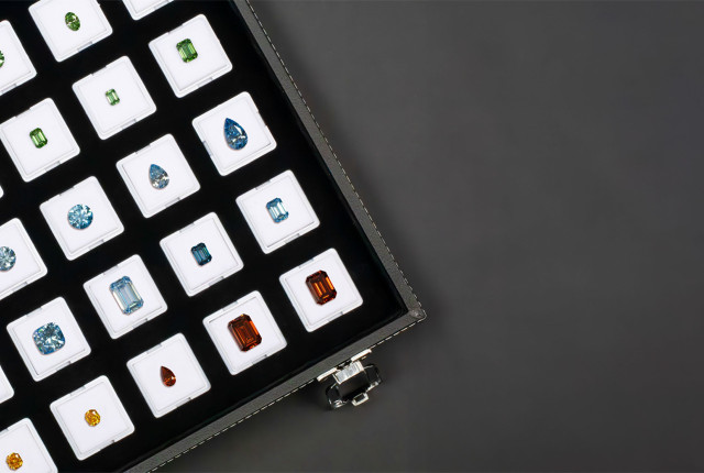 Assorted loose colored diamonds in a black presentation case, including green, blue, orange and yellow cuts