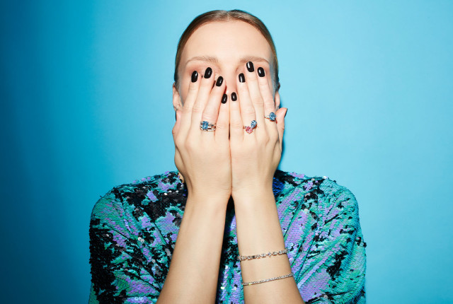 Smiling woman wearing delicate pastel blue and pink gemstone rings on both hands
