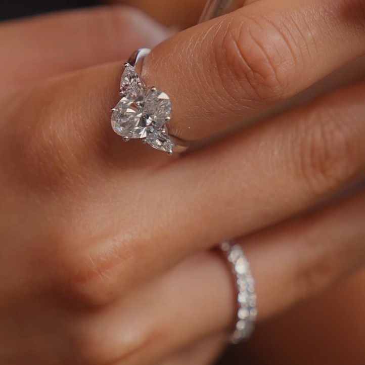 Anillo trilogía con un diamante oval de 3,00 quilates y diamantes pera laterales de 0,35 quilates cada uno en oro rojo