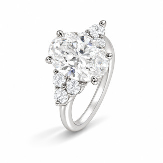 Anillo hecho a medida con un diamante ovalado y piedras laterales redondas dispuestas en racimo