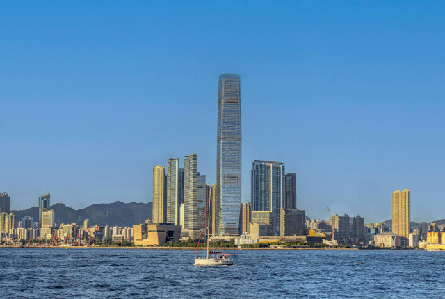 Vue panoramique de Hong Kong avec gratte-ciel, mer calme et voilier au premier plan