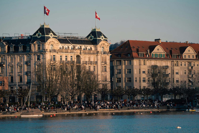 Vue du lac de Zurich avec façades historiques, toits rouges et drapeaux suisses