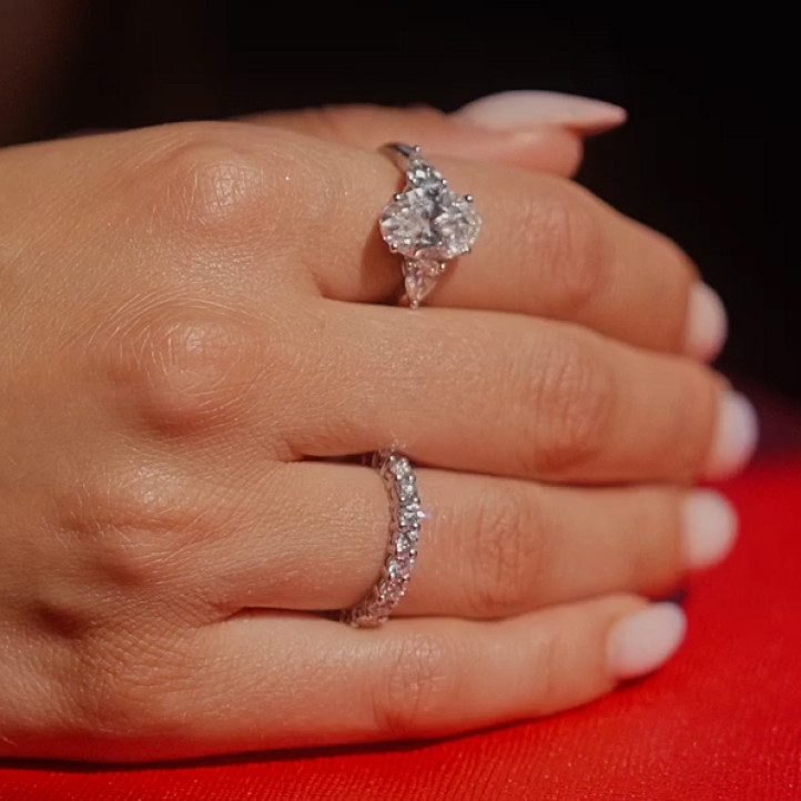 白金三鑽戒指，中間鑲嵌3克拉橢圓形主鑽，兩側各鑲有0.35克拉梨形鑽石