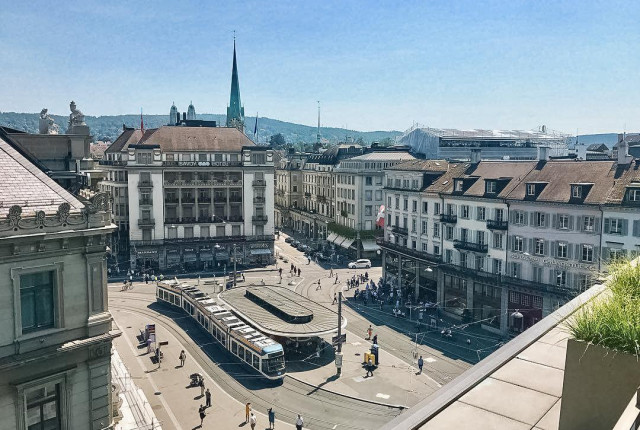 Vista panoramica di Piazza Paradeplatz a Zurigo con tram, edifici storici e campanile verde